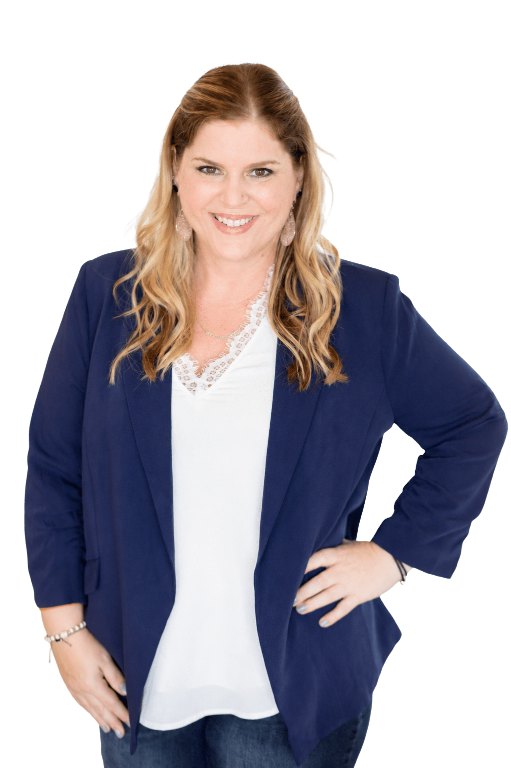 Smiling woman with wavy blonde hair in a navy blazer and white blouse, standing with one hand on her hip.