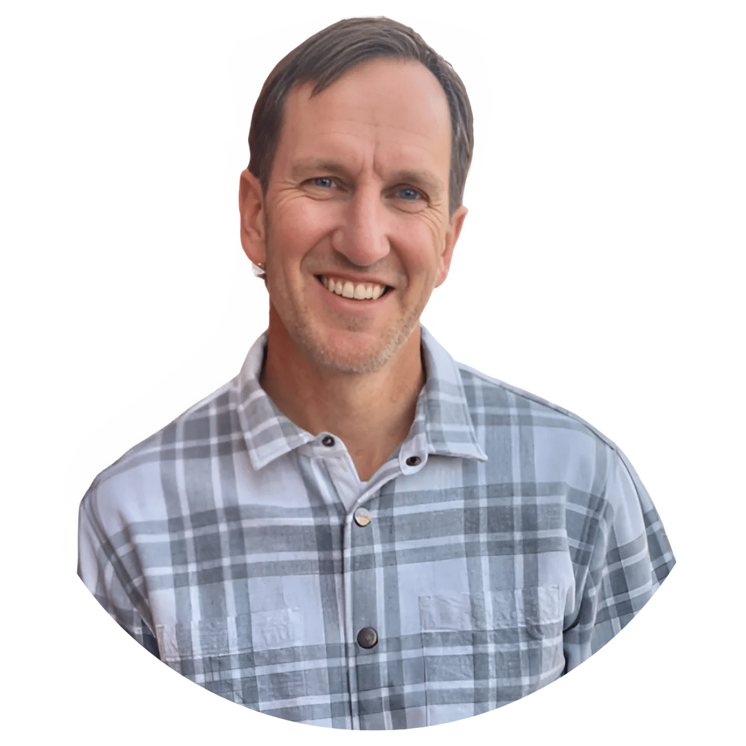 Smiling man in a gray plaid shirt, head and shoulders, on a white background.